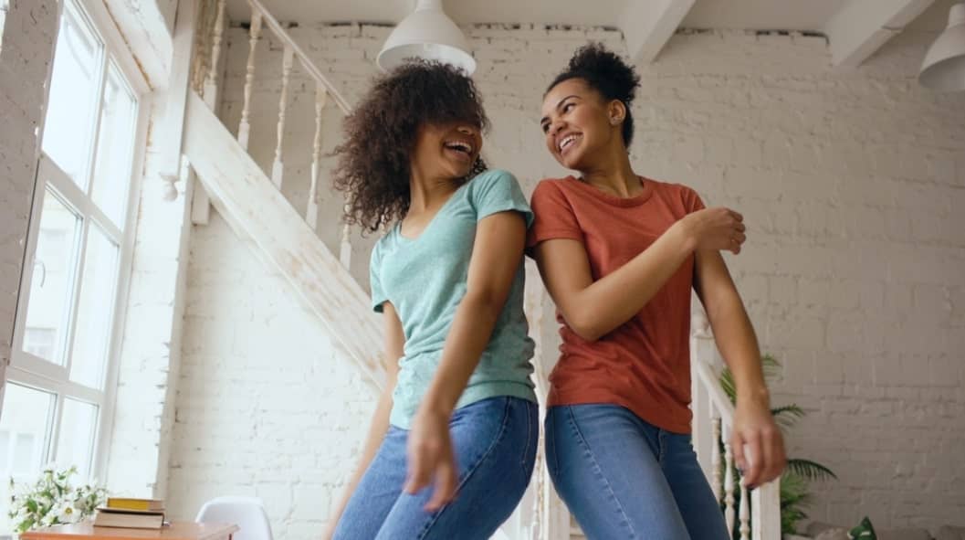 two women looking at each other while dancing happily