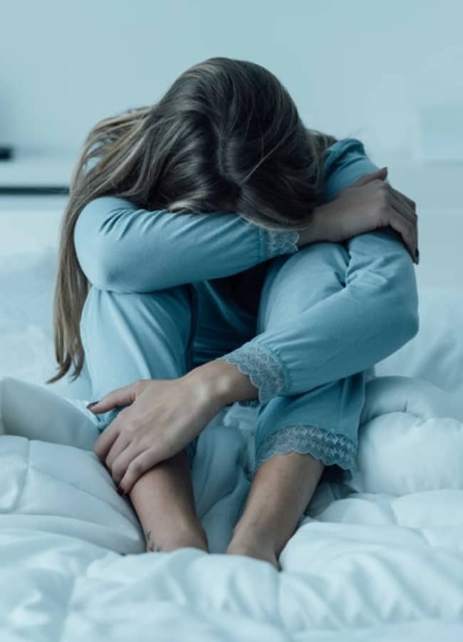 lonely woman sitting on a bed