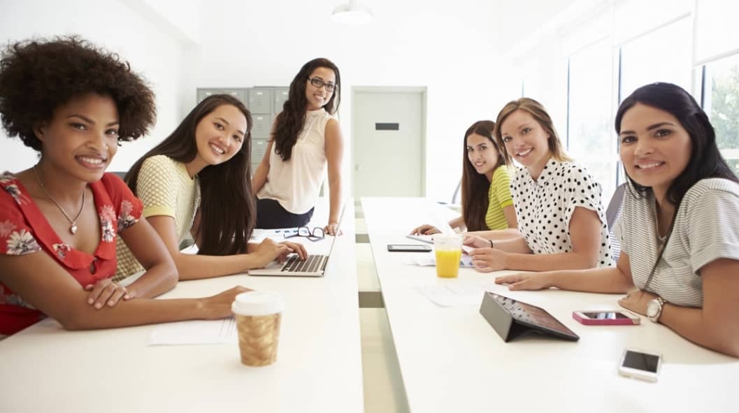 six smiling women having a meeting in a conference room