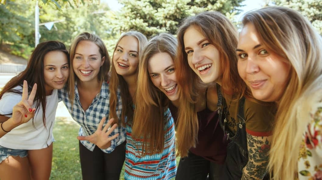 six smiling women standing close to each other