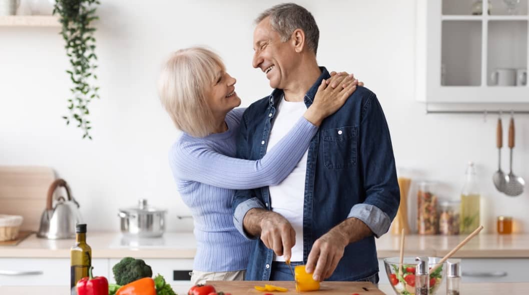 Senior loving couple making healthy salad together in kitchen