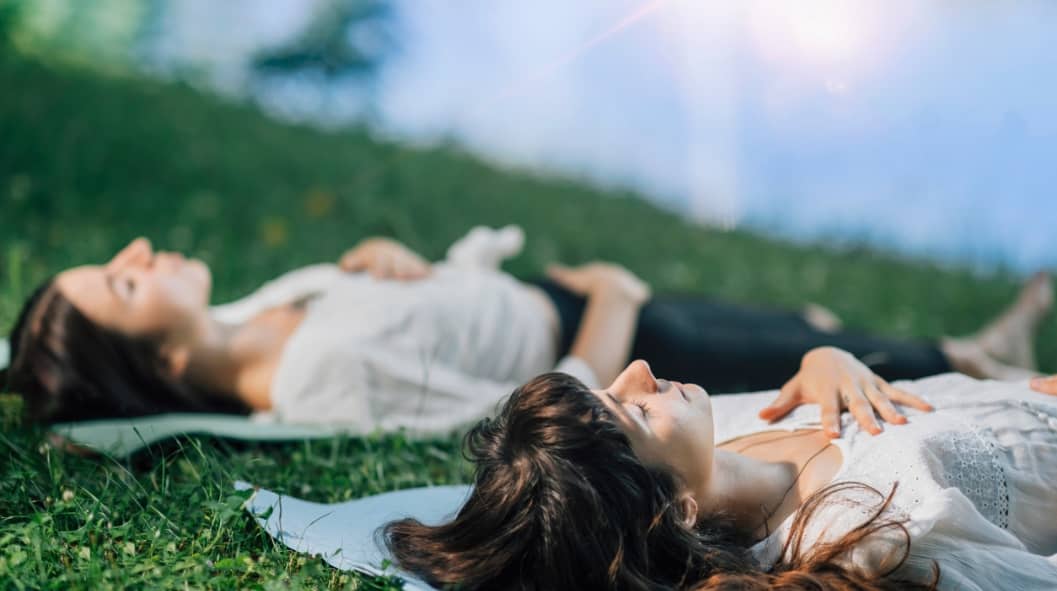 Two young women lying by the water and meditating