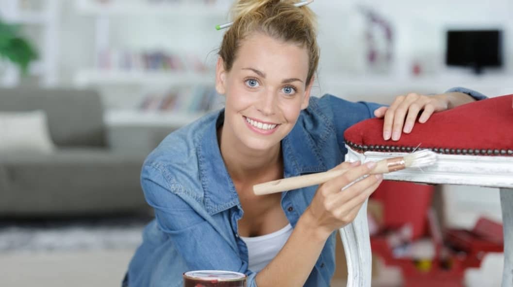 woman painting the leg of a chair