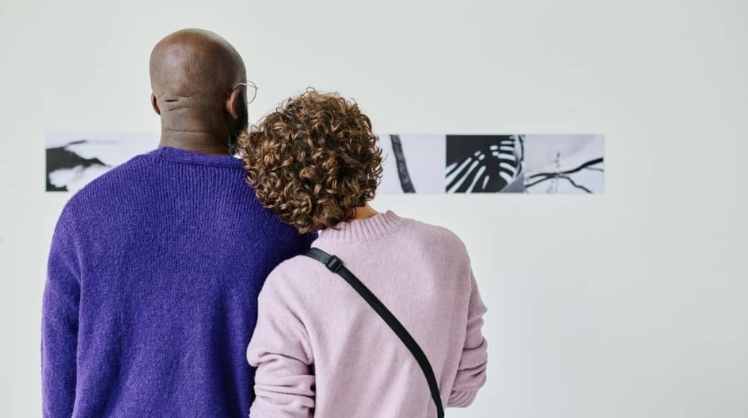 Rear view of young couple watching at modern art together at gallery
