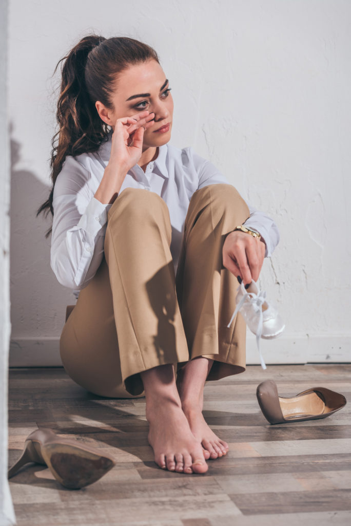 woman crying on the floor while holding a small white shoe