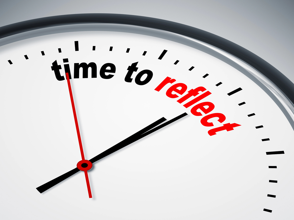 Close-up of a clock face with the words "time to reflect" replacing the numbers. 