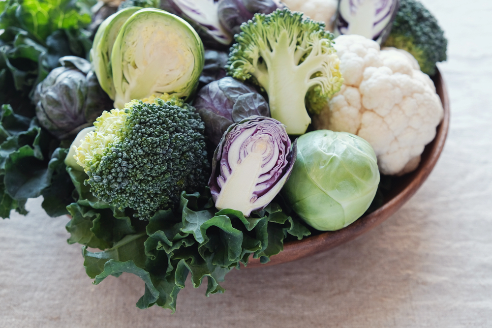 A bowl filled with assorted vegetables including broccoli, Brussels sprouts, kale, and cauliflower