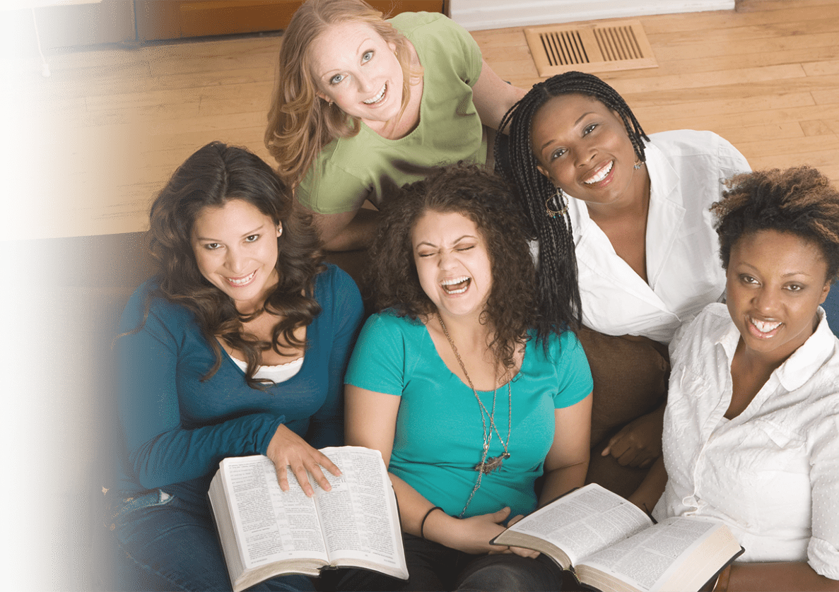 five smiling women sitting on a sofa and holding books