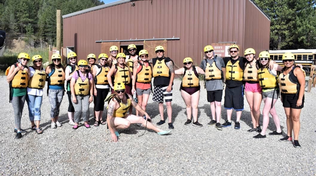 large group of people wearing life vests and outdoor helmets