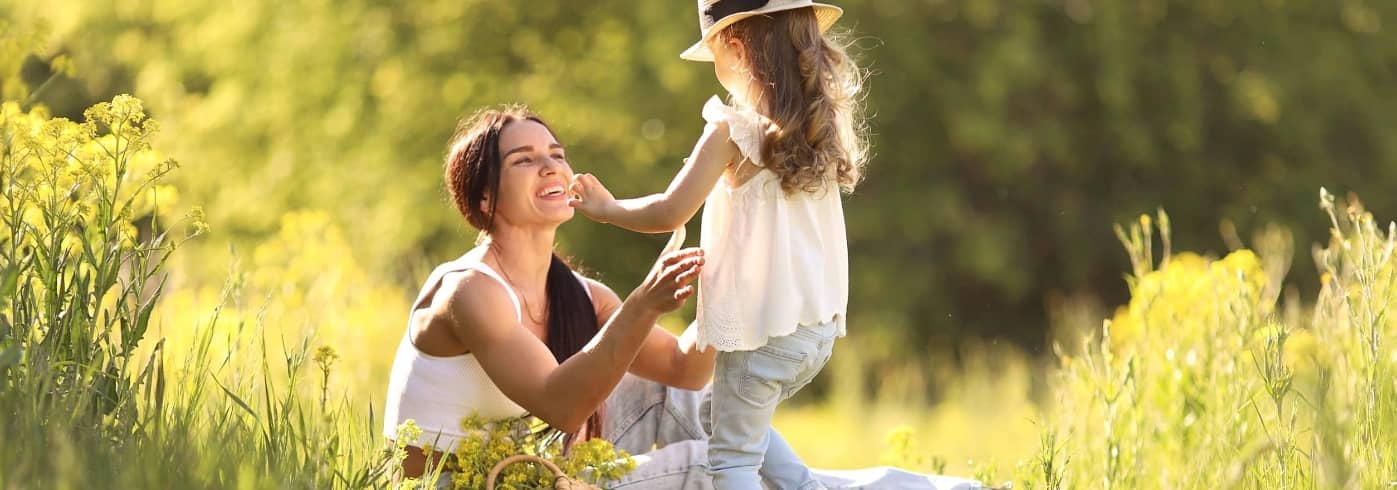 Mother and little daughter having fun in summer meadow with yellow flowers