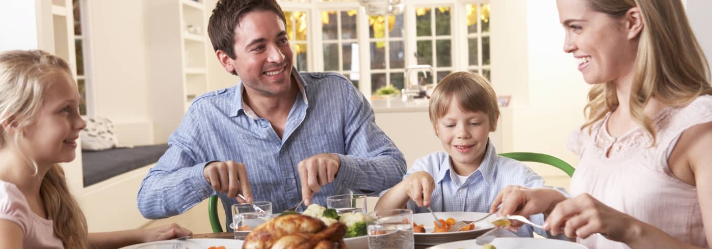 Happy family having roast chicken dinner at table