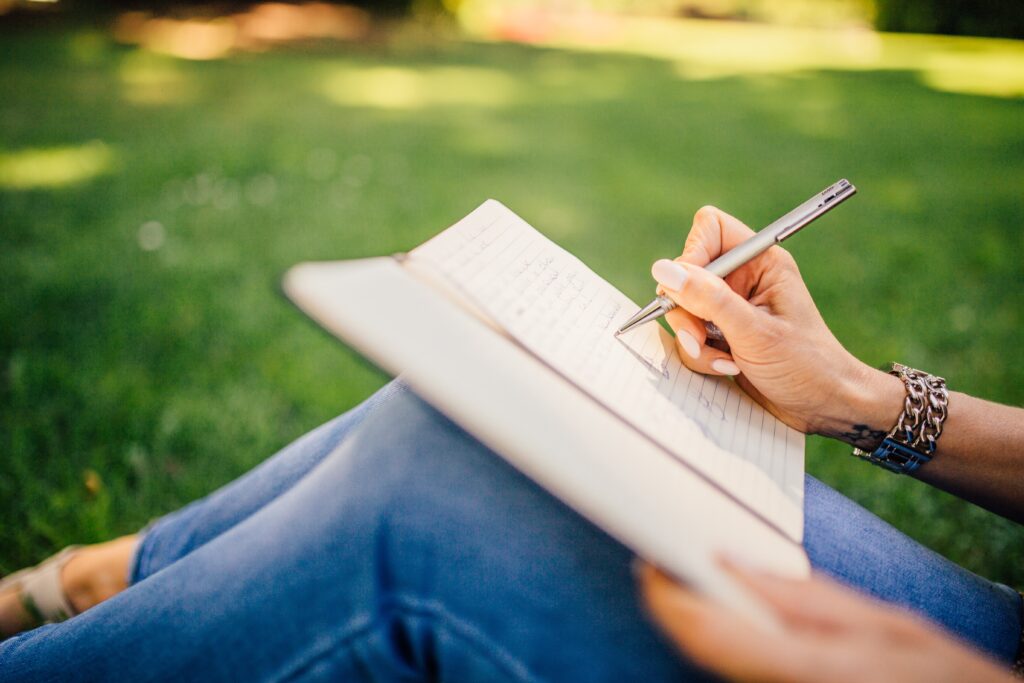 person writing on a notebook outdoors